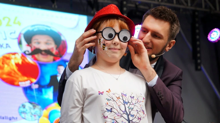 Dziewczynka w komicznych okularach i czerwonym kapeluszu podczas występu iluzjonisty