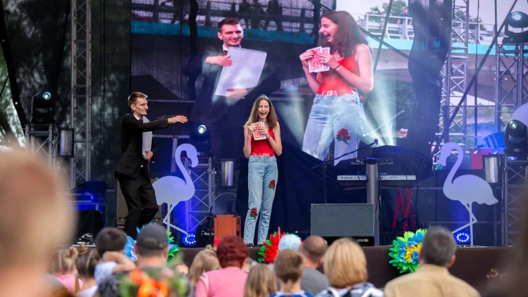 Iluzjonista Konrad Mościński prezentuje na scenie plenerowej trik z dużymi kartami