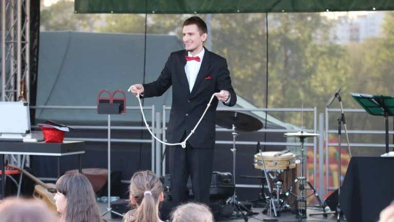 Iluzjonista prezentujący triki ze sznurami i linami podczas plenerowego występu